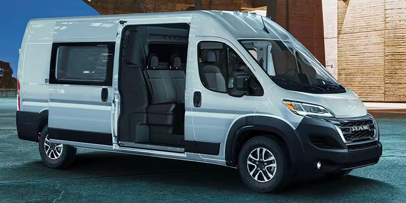 A silver Ram ProMaster passenger van is parked with its side door open